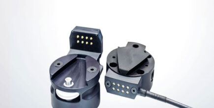 Schneider & Company - Two modern, black multi-pin connectors, one with its cover opened to reveal the metallic pins, against a clean, white background.
